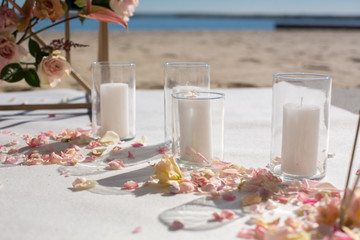 Fresh flower petals lie on the floor next to a decorated wedding arch and white candles. Event decoration with fresh flowers