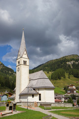View of Church surrauded by mountains  in Arabba village, Dolomites Alps, Italy