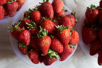 Fresh strawberry in a plastic bowl, close-up, top view, healthy detox food