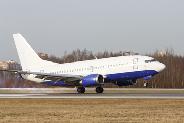 Airplane landing on the runway at the airport with smoke from the chassis, trees on background. Touchdown with tire smoke. Vacation, travel,  aviation concept