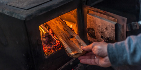 Man putting log to wood burning stove