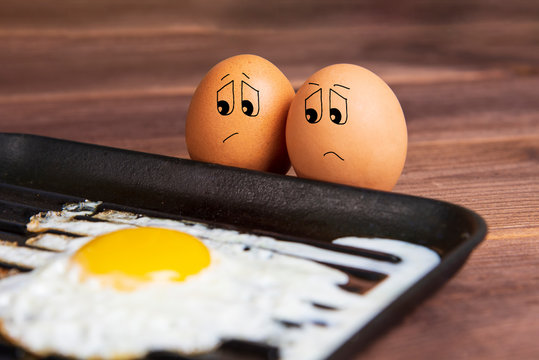 Eggs with a sad face near a fried egg. Humorous picture