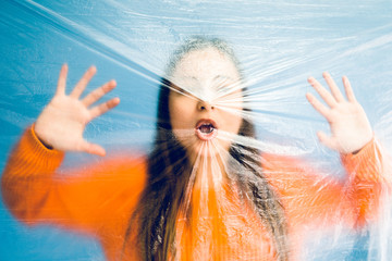 Portrait of teenage girl trapped behind the plastic nylon foil, human rights antipollution...