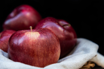 Healthy and organic red apples in a wicker basket on black background