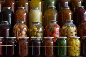 Jars with variety of pickled vegetables and fruits in food market