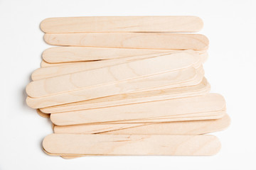 A set of plain and unused wooden crafts sticks strewn artfully on a white background.