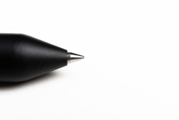 An macro product shot with selective focus of a modern matte finish black barrel ballpoint pen artfully set on a plain white background.
