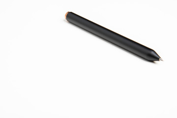 A close-up of a simple minimalistic and sleek black barrel clicker ballpoint pen with selective focus on its writing tip.