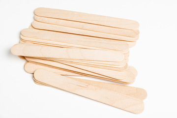A set of plain, unused wide wooden craft sticks strewn artfully on a white background.