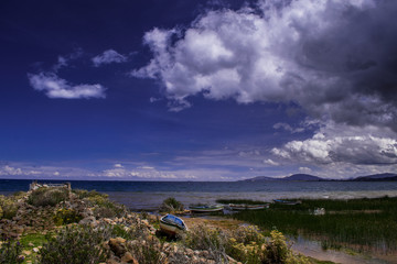 Fotografia a orillas del mistico lago Titicaca en Bolivia con cielo azul y botes en la orilla