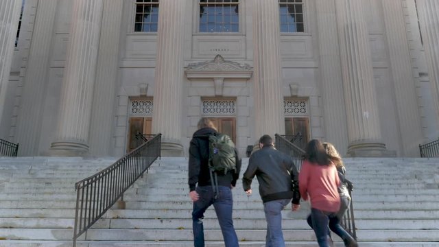 Four college students walking up stairs to a library at a public university