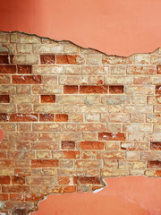Textured wall of red brick and red plaster.