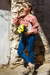 A girl stands near the urban wall with a cup of coffee