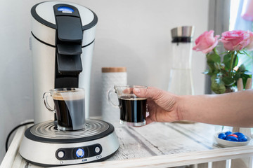 Arm taking away fresh cup of coffee from coffee machine