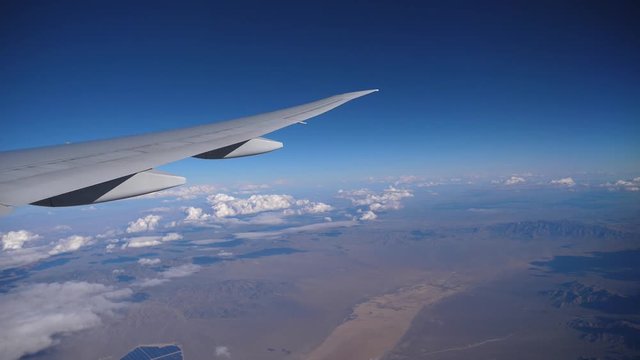 Airplane flight. Wing of an airplane flying above the clouds with sunset sky. View from the window of the plane. Aircraft. Traveling by air.