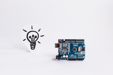 Arduino Uno. Arduino. Micro controller. Technology. Picture of a light bulb in the background. The science. White background.