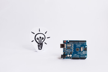 Arduino Uno. Arduino. Micro controller. Technology. Picture of a light bulb in the background. Concept. High intelligence. Idea. - obrazy, fototapety, plakaty
