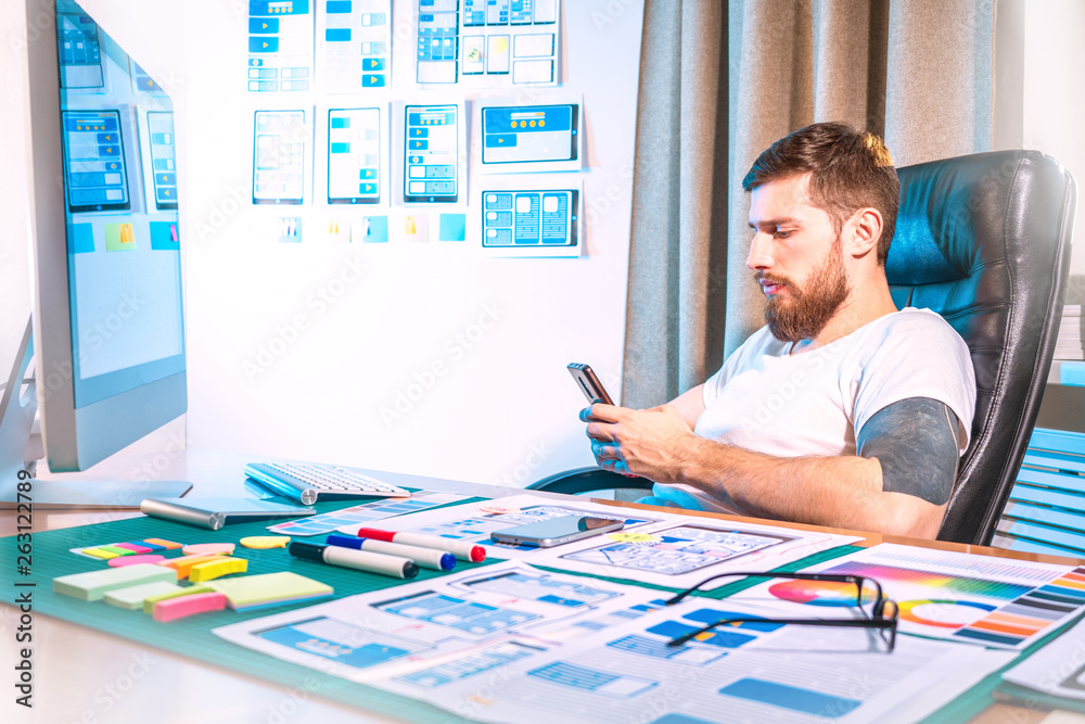 Poster graphic designer testing the application on the phone. design for mobile devices. office of the desi
