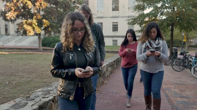 Group of students all on their mobile phones walking and ignoring each others