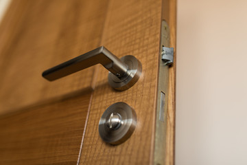 Detail of Modern style metallic door handle on door. Close up