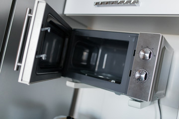 Fototapeta na wymiar Empty microwave oven with open door in kitchen