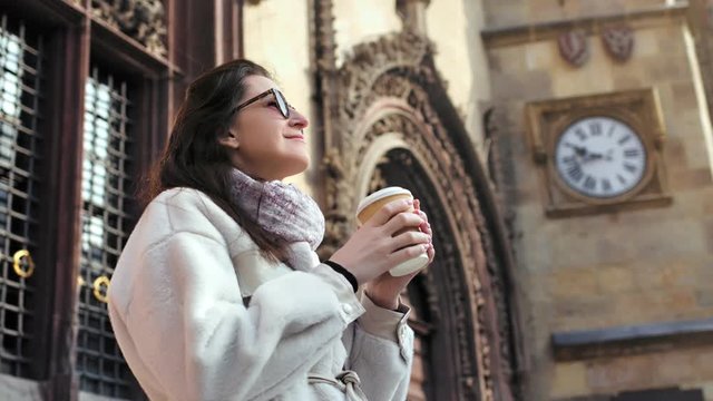 Low angle happy travel girl enjoying wonderful view of vintage castle drinking coffee
