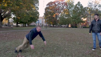 Young man slipping after doing a flip-flop gymnastics move on a college campus