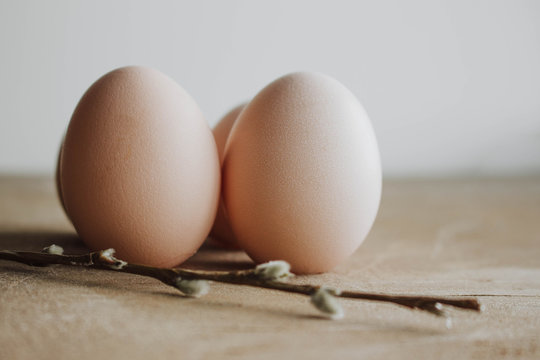Bunch of white eggs with willow branch on wooden background