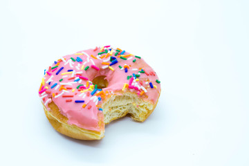 Delicious pink donut with sprinkles bitten into
