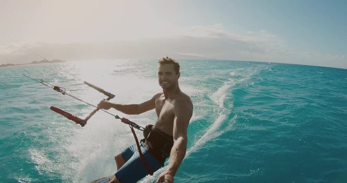 Young athletic man kitesurfing POV in slow motion at sunset, extreme sports POV, tropical island surf adventure