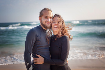 Young couple of happy smiling surfers on the ocean coast, sport  vacation travel concept