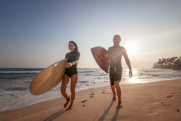 Young beautiful couple of friends on the ocean with surfboards in their hands, sports, active lifestyle, vacation, honeymoon