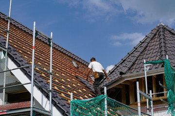 Dachziegel werden durch einen Dachdecker auf einen Neubau befestigt