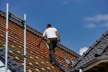 Dachdecker kontrolliert die Dachziegel auf einen Neubau