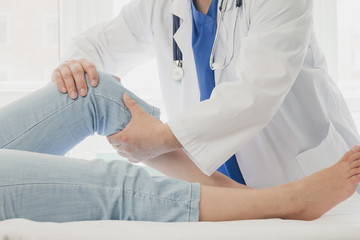 Doctor giving a patient a leg treatment - obrazy, fototapety, plakaty