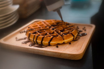 waffles with chocolate sauce on wooden plate. vintage concept