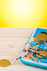 stacking coins and bunch of key on calculator over wooden desk background for home loans concept