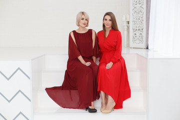 Fashion portrait of women in red dresses in light studio