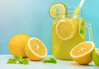 Lemonade drink of soda water, citrus and mint on the light blue background. Cocktail glass with...