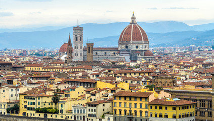 Fototapeta na wymiar Autumn in Florence - A panoramic view of the skyline of the Florence Cathedral, against blue rolling hills and cloudy sky, in the historical Old Town of Florence on a rainy Autumn day. Tuscany, Italy.