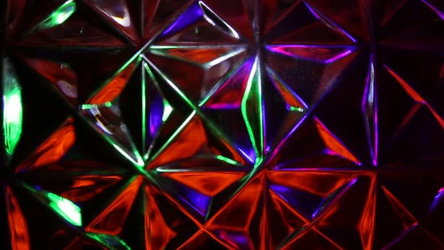 On the background of a rhombus and triangles, the movement of multi-colored rays of light