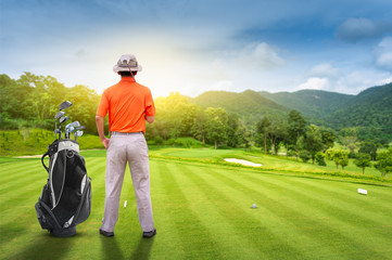 Male golfer teeing off golf ball from tee box on the Course to beautiful sunset