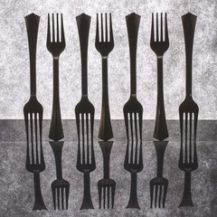 Very simple still life with forks on gray background