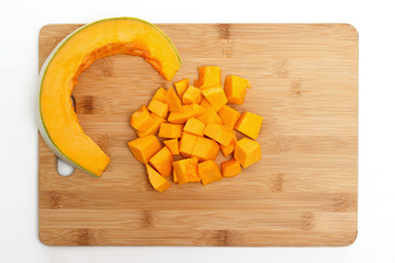 Pumpkin cut into pieces on a wooden board isolated on white background.