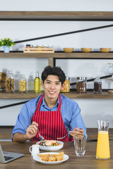 Obraz na płótnie Canvas Asian man eating salad in kitchen. .