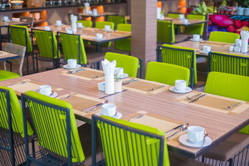 Empty restaurant part of hotel with table and armchair near windows.