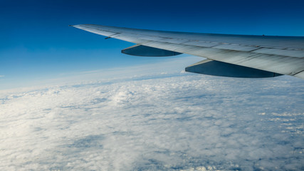 Obraz premium Close up of window with airplane wing. Beautiful cloudscape with clear blue sky.