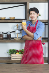 Asian man standing and drinking orange juice ..