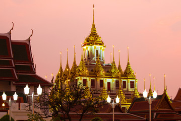 Naklejka premium View of the top of the old Chedi Loha Prasat in lilac twilight. Bangkok, Thailand