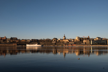 Fototapeta premium A sunny early spring day in Stockholm, view over a pier with boats and birds at the old town and the Södermalm district 